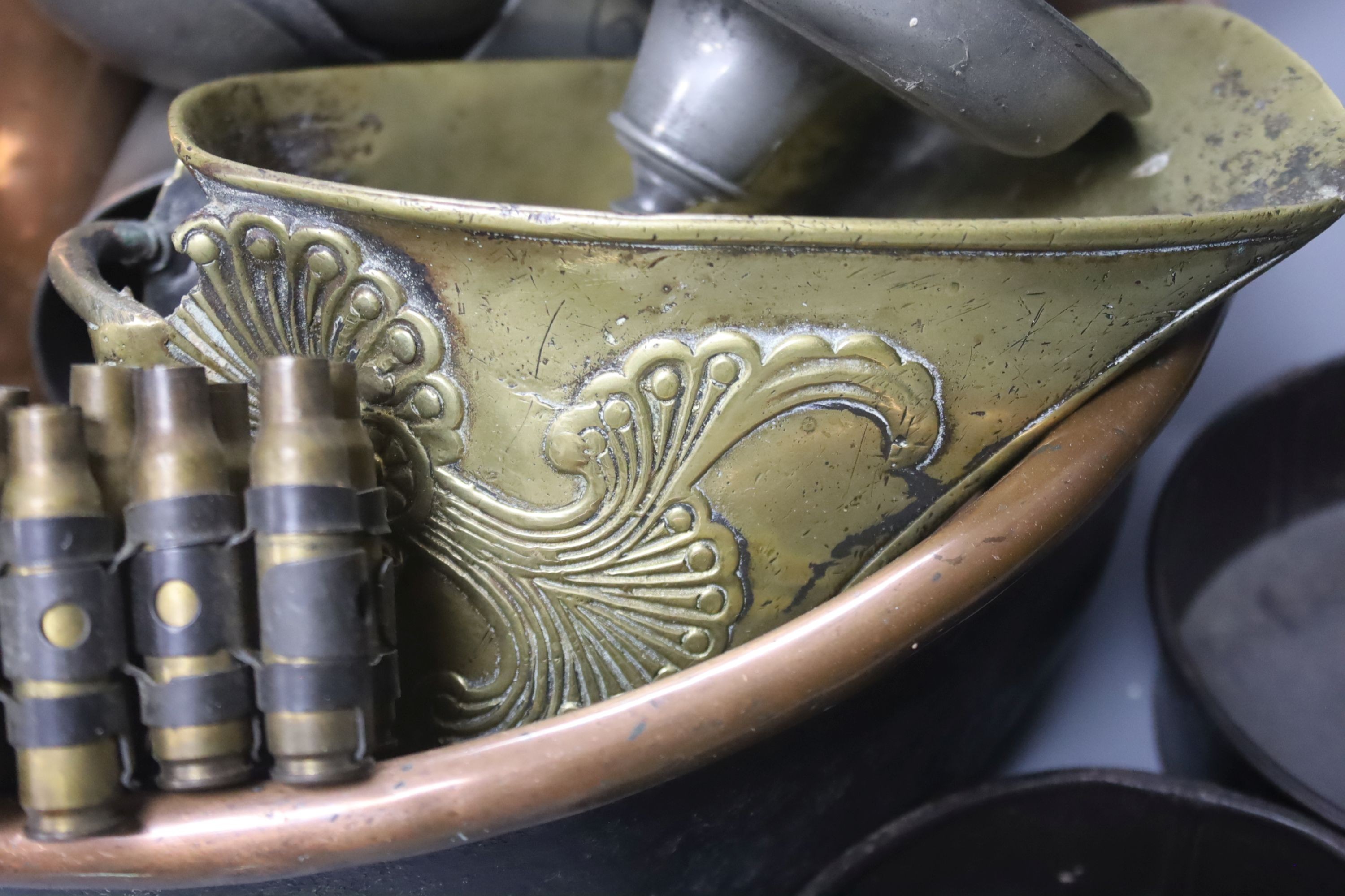 A group of assorted metalware including a copper pan, a brass stirrup, a pewter mug filled with pewter spoons, and a pair of toleware coasters